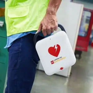 Man holding a Lifepak CR2 Defibrillator with jeans and a shirt on