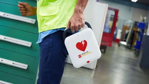 Man holding a Lifepak CR2 Defibrillator with jeans and a shirt on