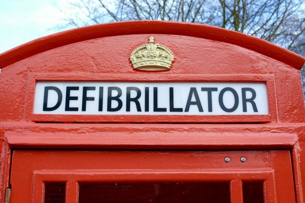 Sign of Defibrillator at the top of a telephone box